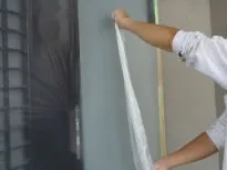 ドアやサッシ窓など、塗料を塗らない部分をビニールで覆うなどして汚れないよう養生作業をします。